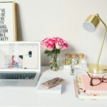Schreibtisch mit Laptop, Lampe und Rosen auf dem Tisch