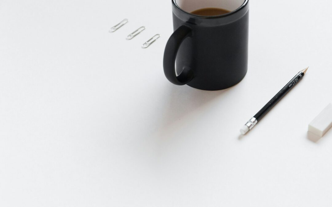Kaffeebecher, Bleistift, Radiergummi und Büroklammern auf Schreibtisch