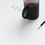 Kaffeebecher, Bleistift, Radiergummi und Büroklammern auf Schreibtisch