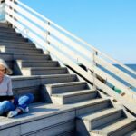 Frau lesend auf Treppe sitzend