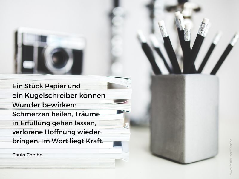 Stift, Papier, Fotoapparat und der Spruch Ein Stück Papier und ein Kugelschreiber können Wunder bewirken: Schmerzen heilen, Träume in Erfüllung gehen lassen, verlorene Hoffnung wieder-bringen. Im Wort liegt Kraft. von Paulo Coelho