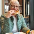 Marita Eckmann Brezel essend in Café