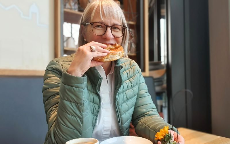 Marita Eckmann Brezel essend in Café