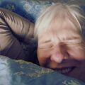 Frau mit zugekniffenen Augen im Bett liegend