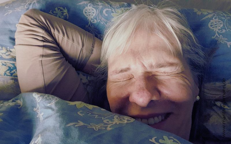 Frau mit zugekniffenen Augen im Bett liegend