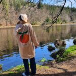 Frau mit Mantel steht am Ufer des Deininger Weiher