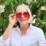 Frau mit roter Herzbrille, die sie abnimmt